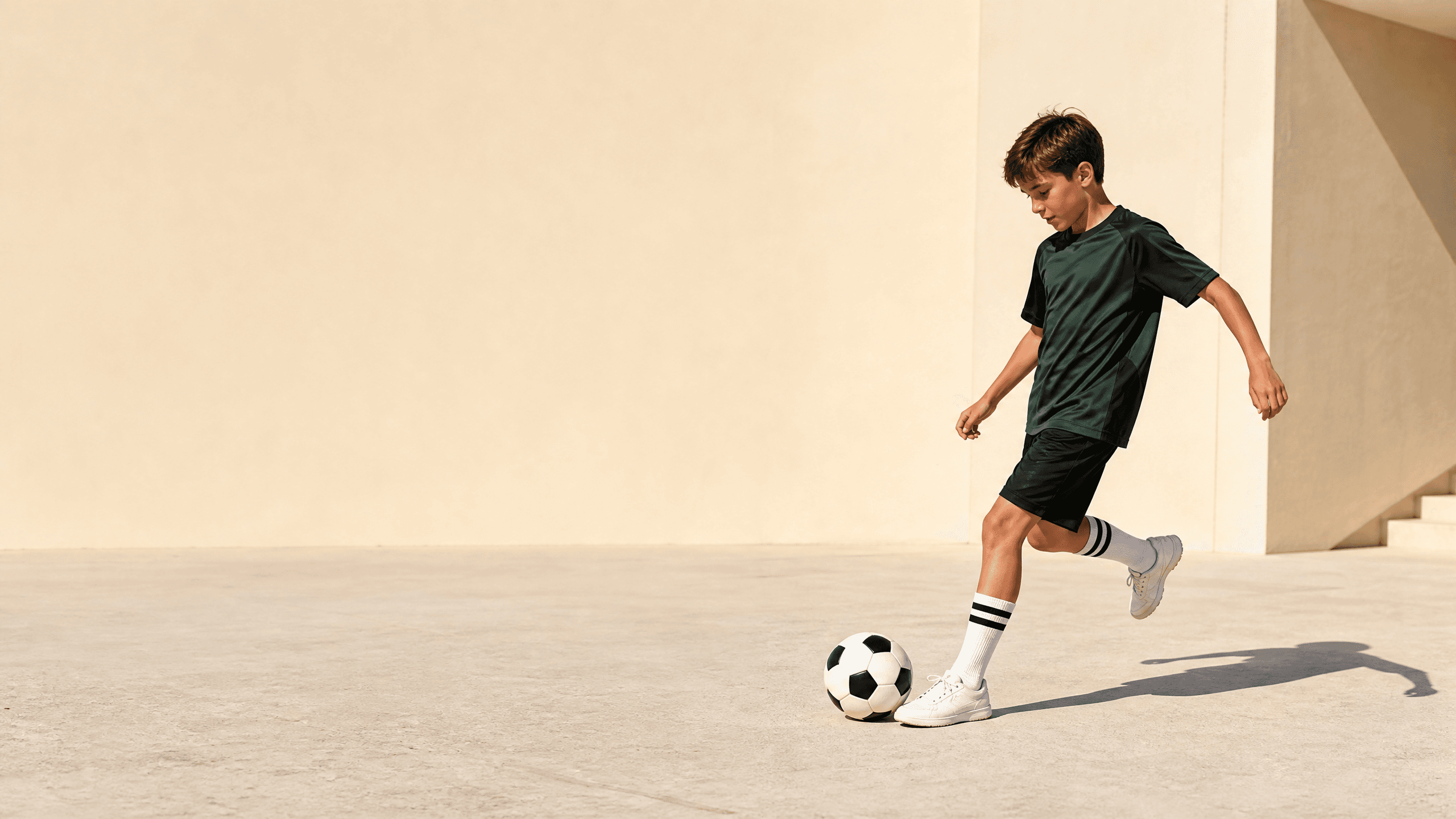 Young football player controlling a ball on a bright court